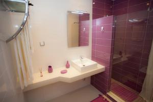 a bathroom with a sink and a shower with purple tiles at Surf and Stones Apartment in Peniche