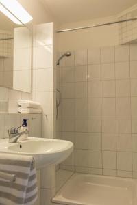ein weißes Bad mit einem Waschbecken und einer Dusche in der Unterkunft Gästehaus Margareth in Büsum