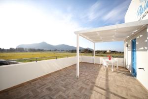 une pergola blanche sur un balcon avec une table dans l'établissement Plaia Resort, à Favignana