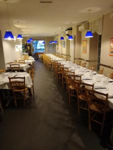 una grande sala da pranzo con tavoli bianchi e sedie in legno di Hotel Belvedere a Lovere