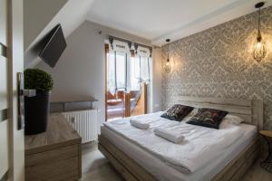 um quarto com uma cama com lençóis brancos e almofadas em udanypobyt Apartamenty Skocznia em Zakopane