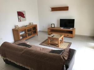 a living room with a couch and a tv at Swieqi Semi Detached Maisonette in St. Julianʼs