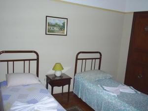 a bedroom with two beds and a table with a lamp at Parque Hotel Morro Azul - a 12 km do Parque dos Dinossauros in Morro Azul