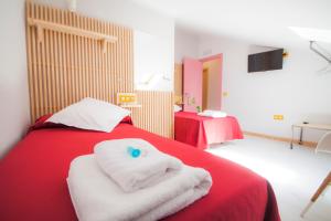 Un dormitorio con una cama roja con toallas. en Pension Restaurante Casa Camiño, en Palas de Rei 