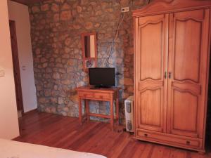 Habitación con TV en una mesa y armario de madera. en Ablanera 2, en Cangas de Onís