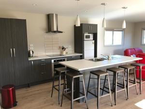 a kitchen with black cabinets and a kitchen island with bar stools at Cromwell Safari Bach in Cromwell