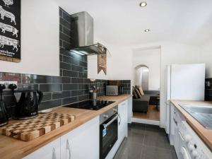 a kitchen with white cabinets and black tiles on the wall at Cambridge House in Luton