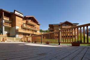 una terraza de madera frente a algunos edificios en CGH Résidences & Spas Les Clarines, en Les Menuires