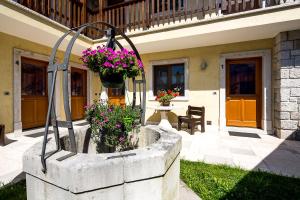 a fountain in the yard of a house with flowers at Lokanda Devetak in Savogna dʼIsonzo