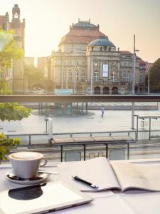 ein offenes Buch auf einem Tisch mit einer Tasse Kaffee in der Unterkunft Hotel an der Oper in Chemnitz