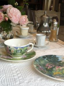 EchinghenにあるLe Prince Gourmandの皿、カップ、花が並ぶテーブル