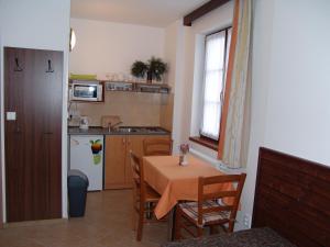 eine kleine Küche mit einem Tisch, einem Tisch und Stühlen in der Unterkunft Apartmány U Kamínku in Janské Lázně