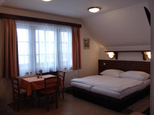 a bedroom with a bed and a table and windows at Apartmány U Kamínku in Janske Lazne