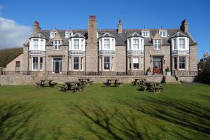 a large building with picnic tables in front of it at Kilmarnock Arms Hotel in Cruden Bay