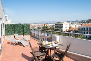 a balcony with a table and chairs on a roof at Hotel Abrial by Soniho in Cannes