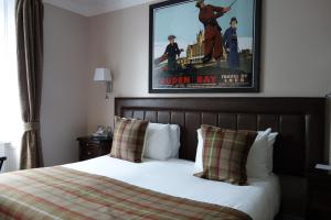 a bed in a hotel room with a poster on the wall at Kilmarnock Arms Hotel in Cruden Bay