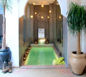 a swimming pool in a building with a palm tree at Riad Chayma Marrakech in Marrakech