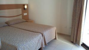 リョレート・デ・マルにあるApartamentos Selvaparkのベッド2台と窓が備わるホテルルームです。