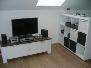 ein Wohnzimmer mit einem TV und einem weißen Regal in der Unterkunft Ferienwohnung Rheinaue in Köln