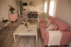 ein Wohnzimmer mit einem rosa Sofa und einem Tisch in der Unterkunft Apartamento El Balcon de la Muralla in Córdoba