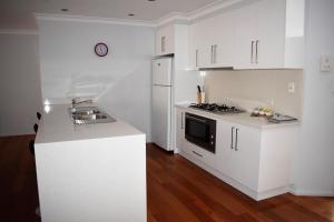a kitchen with white cabinets and white appliances at Griffith Prestige Apartments in Griffith