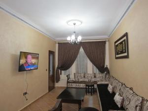 een woonkamer met een bank en een tv aan de muur bij Résidence familiale "Les Jardins de Cabo" in Cabo Negro