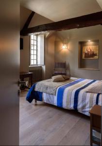 um quarto com uma cama com riscas azuis e brancas em La Porterie em Souvigny