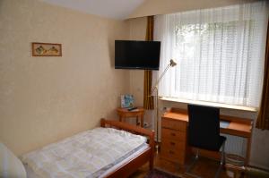 Schlafzimmer mit einem Bett, einem Schreibtisch und einem TV in der Unterkunft Hotel Waldersee in Hannover