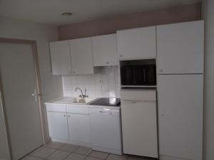 a kitchen with white cabinets and a sink and a microwave at Le Hameau de l'Ocean in Saint-Hilaire-de-Riez