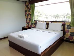 1 dormitorio con 1 cama blanca grande y ventana en โรงแรมฟ้าพราวฝน Fah Proud Fon Hotel en Nakhon Ratchasima