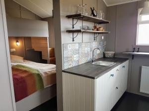 a small bathroom with a sink and a bed at Grásteinn Guesthouse in Þórshöfn