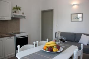a table with a bowl of fruit and a glass of wine at Angelique Apartment in Antiparos