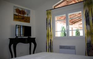 a bedroom with a bed with a television and a window at Maison de Margot in Peyriac-Minervois