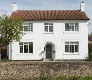 een wit huis met een stenen muur bij Callender House in Harrogate