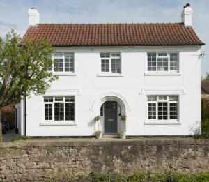 uma casa branca com uma parede de tijolos em Callender House em Harrogate