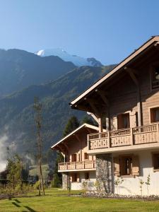 a building with a balcony and mountains in the background at CGH Résidences & Spas Le Hameau De Pierre Blanche in Les Houches