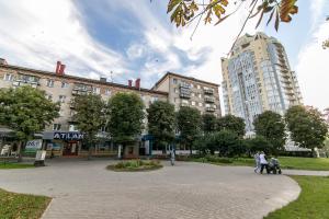 a group of people walking in a park with buildings at Апартаменты в центре на проспекте Мира от ApartmentCity in Mogilev