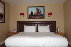 a bed in a hotel room with a poster on the wall at Kilmarnock Arms Hotel in Cruden Bay