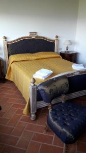 a bed with a yellow blanket and a chair in a room at Residenza Il Platano Fortilizio di Campiglia in Rapolano Terme