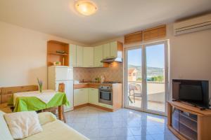a kitchen with a living room with a table and a television at Apartments Tatjana in Cres