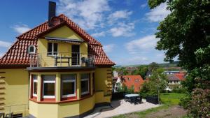 Casa amarilla con balcón y mesa en Villa Am Ehrensteig, en Eisenach
