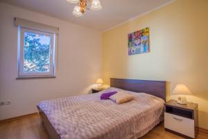 a bedroom with a bed and two lamps and a window at Apartments Tatjana in Cres
