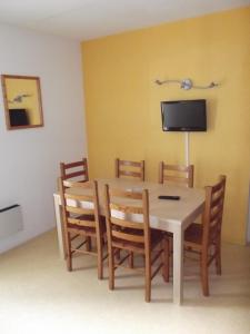 a dining room table with chairs and a tv on the wall at Résidence L'Océane, Andernos in Andernos-les-Bains