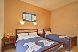 two beds in a hotel room with towels on them at Nikos Apartments in Falasarna
