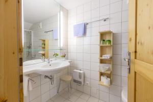 a white bathroom with a sink and a mirror at Frühstückspension "Schlosswirt" in Ossiach