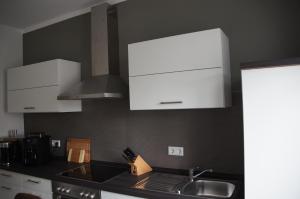 a kitchen with white cabinets and a sink at Ferienwohnung Markkleeberg Ost-See in Markkleeberg