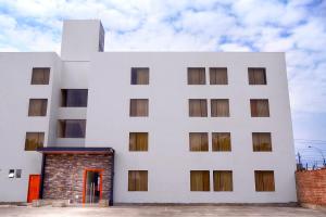 un edificio blanco con una puerta roja en Hotel Hacienda Lima Norte en Lima