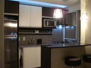 cocina con armarios blancos y nevera de acero inoxidable en Apartamento Cristal, en Porto Alegre