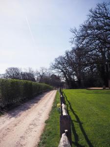 a dirt road with a fence next to a field at Old Dairy Farm Glamping in Emsworth
