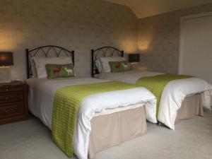 two beds in a bedroom with green and white sheets at Torbeag House in Fort William